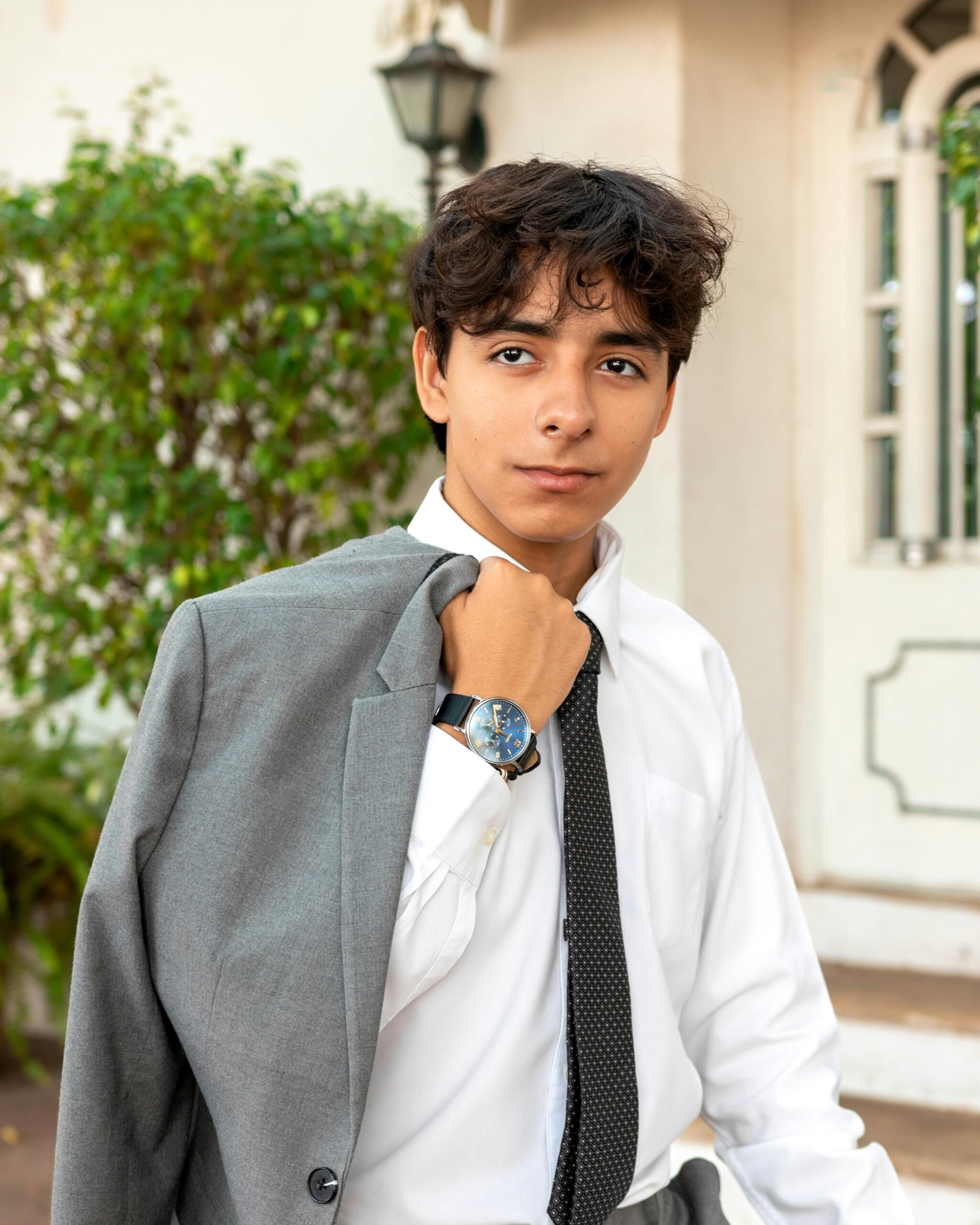 Confident teenager holding a grey suit jacket outdoors in Mérida, Mexico.